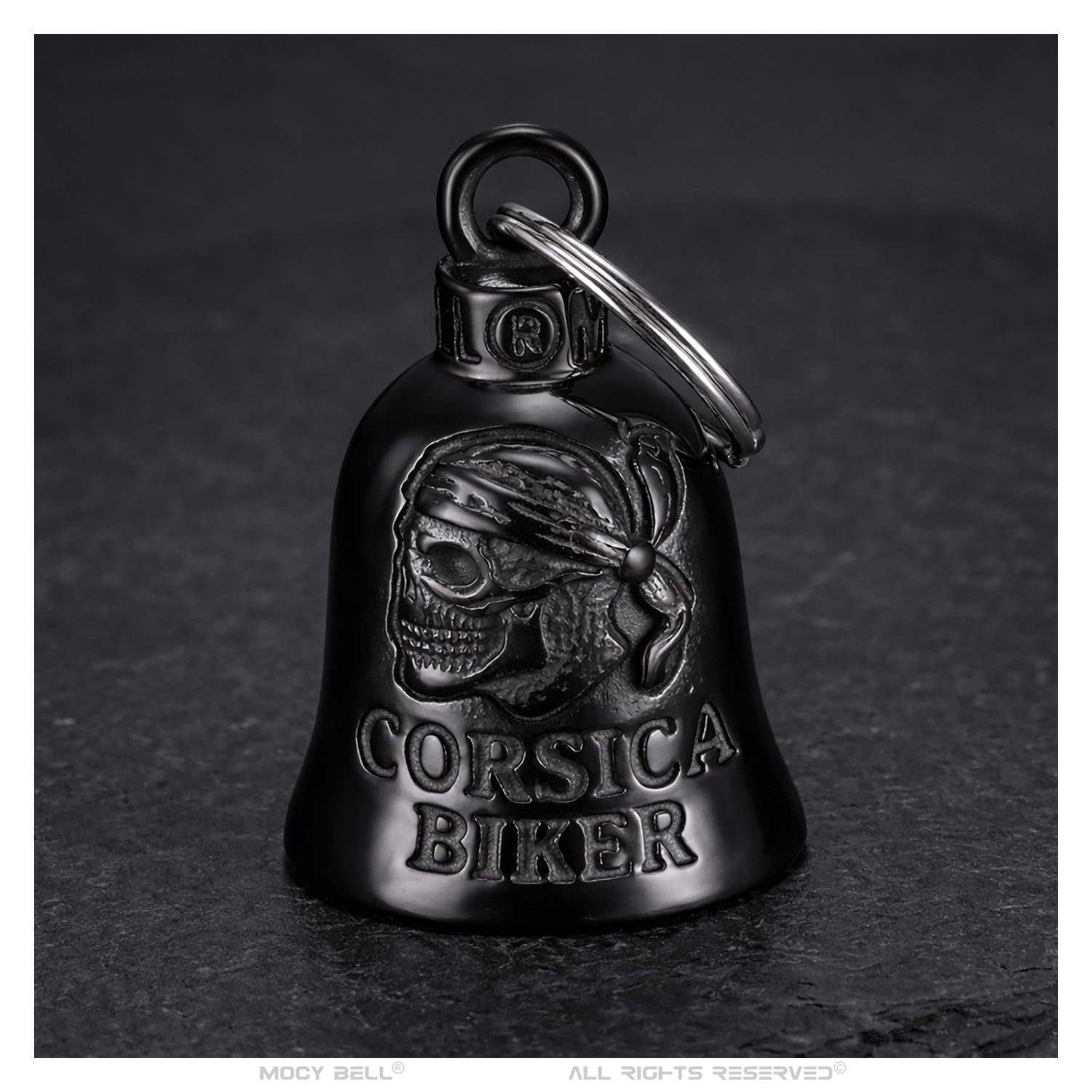 Clochette moto Corsica Biker noir titane posée sur fond sombre avec éclairage contrasté